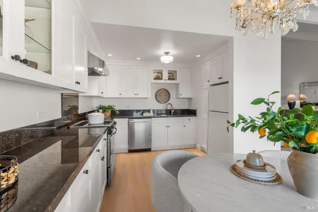 a kitchen with stainless steel appliances granite countertop a refrigerator a stove a sink and white cabinets