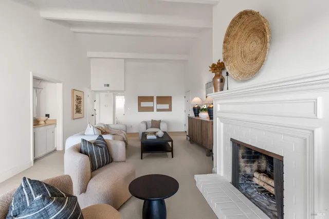 a living room with furniture a rug a fireplace and a window