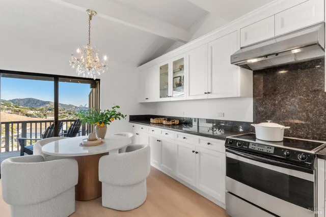 a kitchen with stainless steel appliances granite countertop a white cabinets a stove and a chandelier