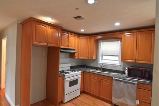 73 Hamilton Street Boston, MA 02125 - Photo 8 of 21 a kitchen with granite countertop a refrigerator a sink a stove and cabinets