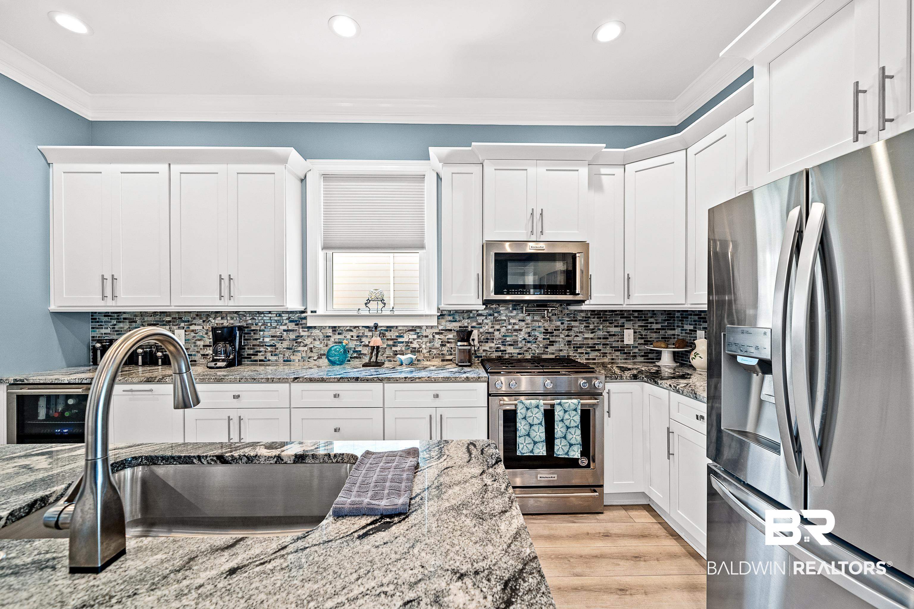 12329 Reunion Place, Unit LOT 38 Foley, AL 36535 - Photo 10 of 43 Kitchen featuring stainless steel appliances, crown molding, white cabinets, light stone counters, and tasteful backsplash