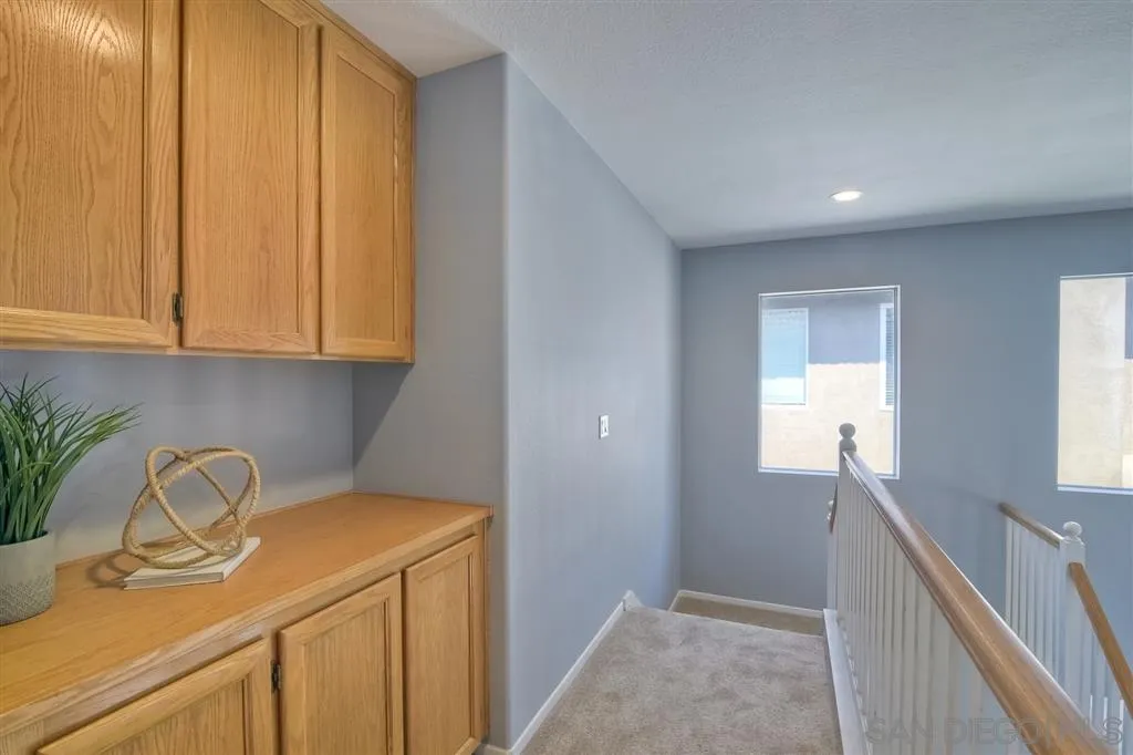 11574 Village Ridge Road San Diego, CA 92131 - Photo 22 of 25 a hallway with a sink and cabinets