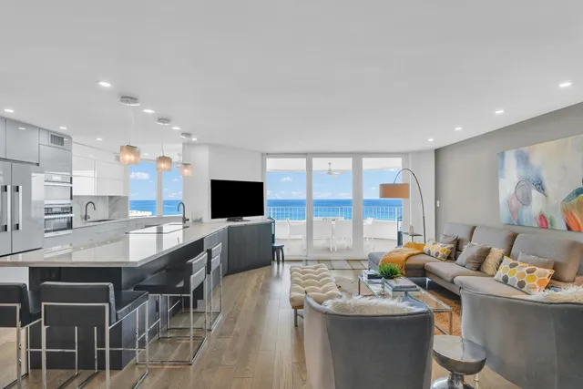 a living room with furniture kitchen view and a large window