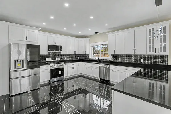 a kitchen with granite countertop a stove sink cabinets and refrigerator