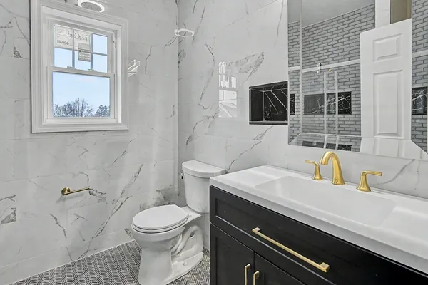 a bathroom with a granite countertop toilet sink and mirror