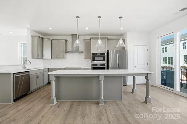 a kitchen with stainless steel appliances granite countertop a sink a stove a refrigerator and a oven with wooden floor