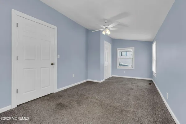 an empty room with windows and chandelier fan