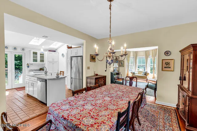 a open kitchen with stainless steel appliances granite countertop a stove top oven a refrigerator a dining table and chairs with wooden floor