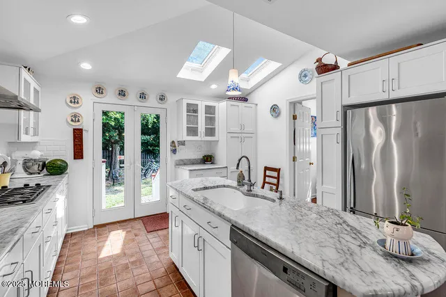 a kitchen with stainless steel appliances granite countertop a sink refrigerator and cabinets