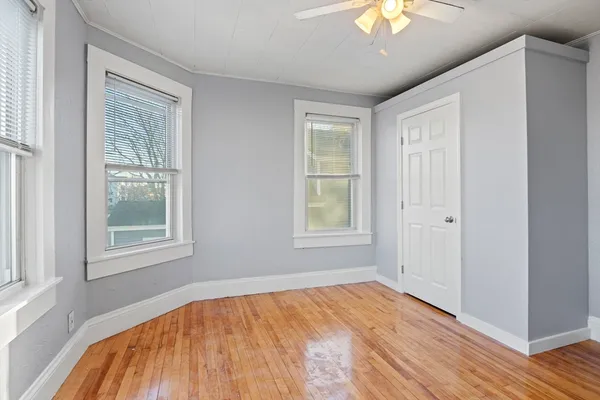a view of empty room with wooden floor and fan
