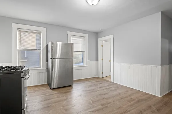 a view of a kitchen with refrigerator and wooden floor