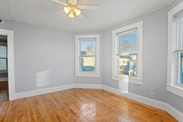 a view of empty room with wooden floor and fan
