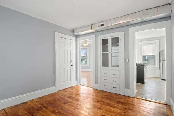 a view of an empty room with window and wooden floor