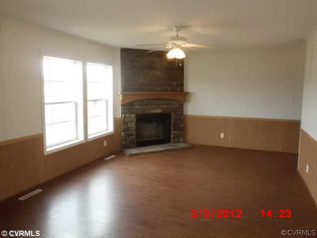3709 Wakema Road West Point, VA 23181 - Photo 4 of 8 an empty room with wooden floor fireplace and windows