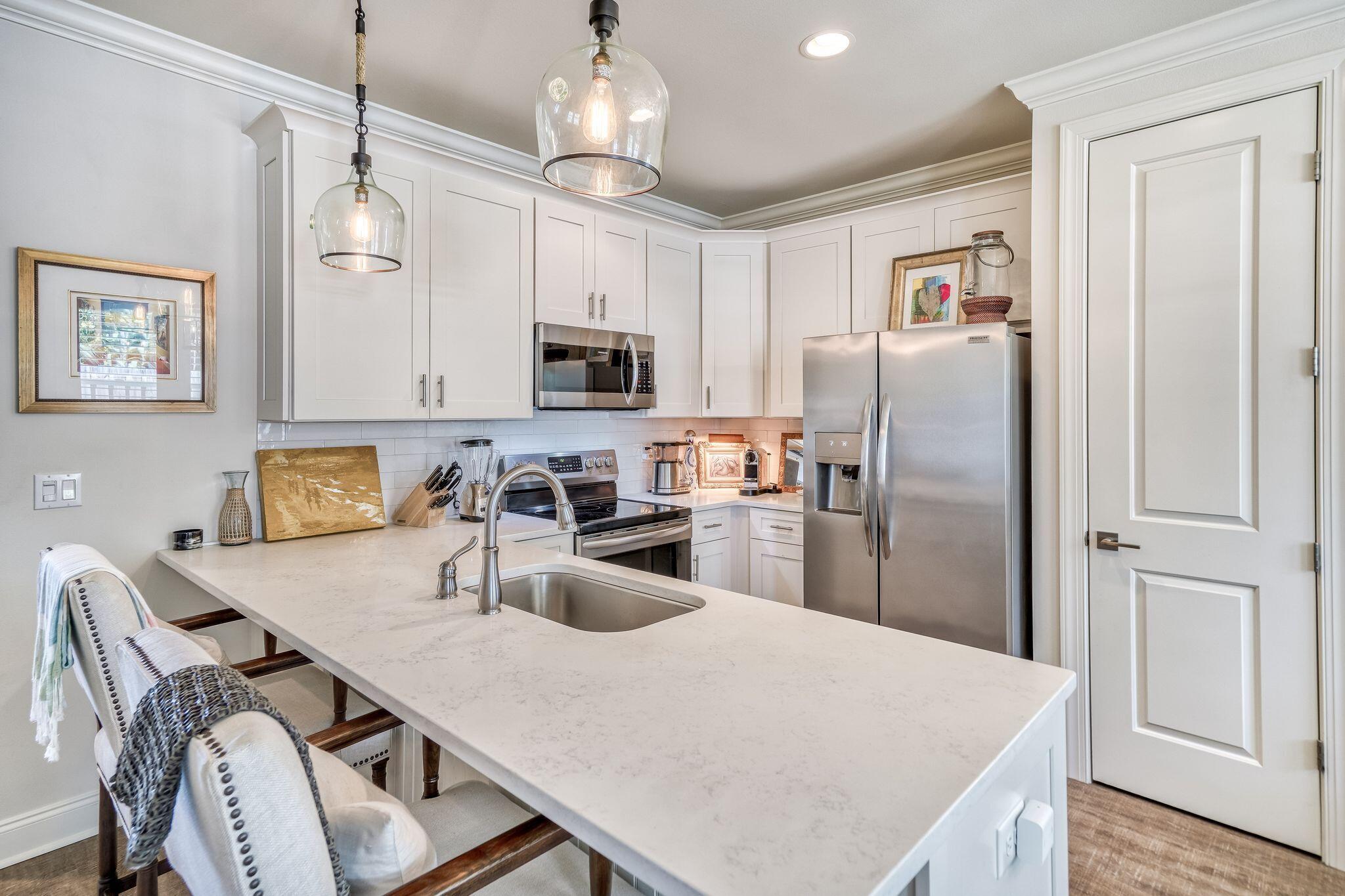 80 North Zander Way Santa Rosa Beach, FL 32459 - Photo 27 of 49 a kitchen with stainless steel appliances granite countertop a refrigerator a stove a sink dishwasher a dining table and chairs with wooden floor