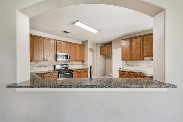 a kitchen with stainless steel appliances granite countertop a sink stove refrigerator granite counter tops and window