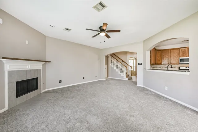 a view of a livingroom with an empty kitchen and a fireplace