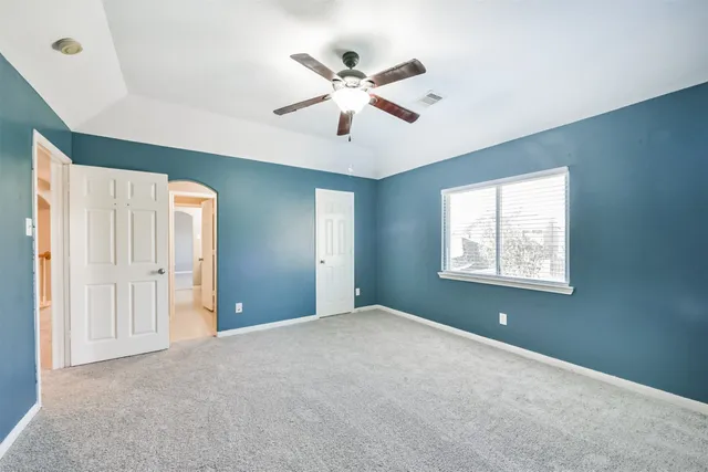 a view of an empty room with window and a ceiling fan
