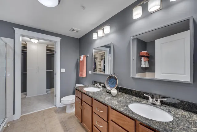 a bathroom with double vanity sinks a toilet a mirror and shower