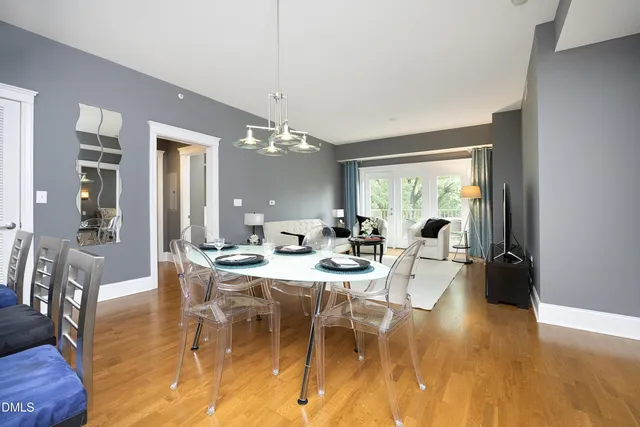 a view of a dining room and livingroom with furniture wooden floor a chandelier