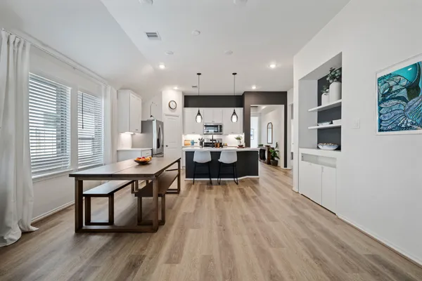 a living room with stainless steel appliances furniture a window and wooden floor
