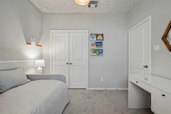 a bedroom with a bed and a lamp on dresser