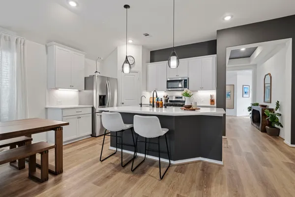 a kitchen with granite countertop a table chairs stove a refrigerator and cabinets