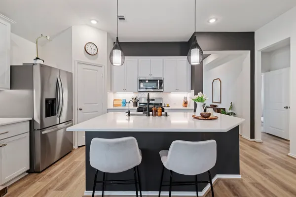 a kitchen with stainless steel appliances granite countertop a table chairs refrigerator and microwave