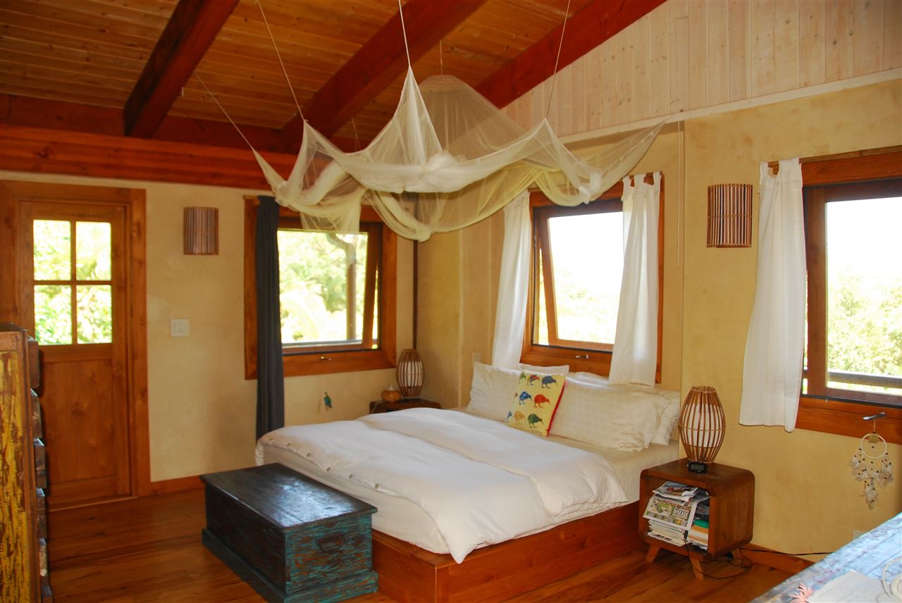 56 West Waipio Road Haiku, HI 96708 - Photo 10 of 25 a bedroom with a bed and wooden floor