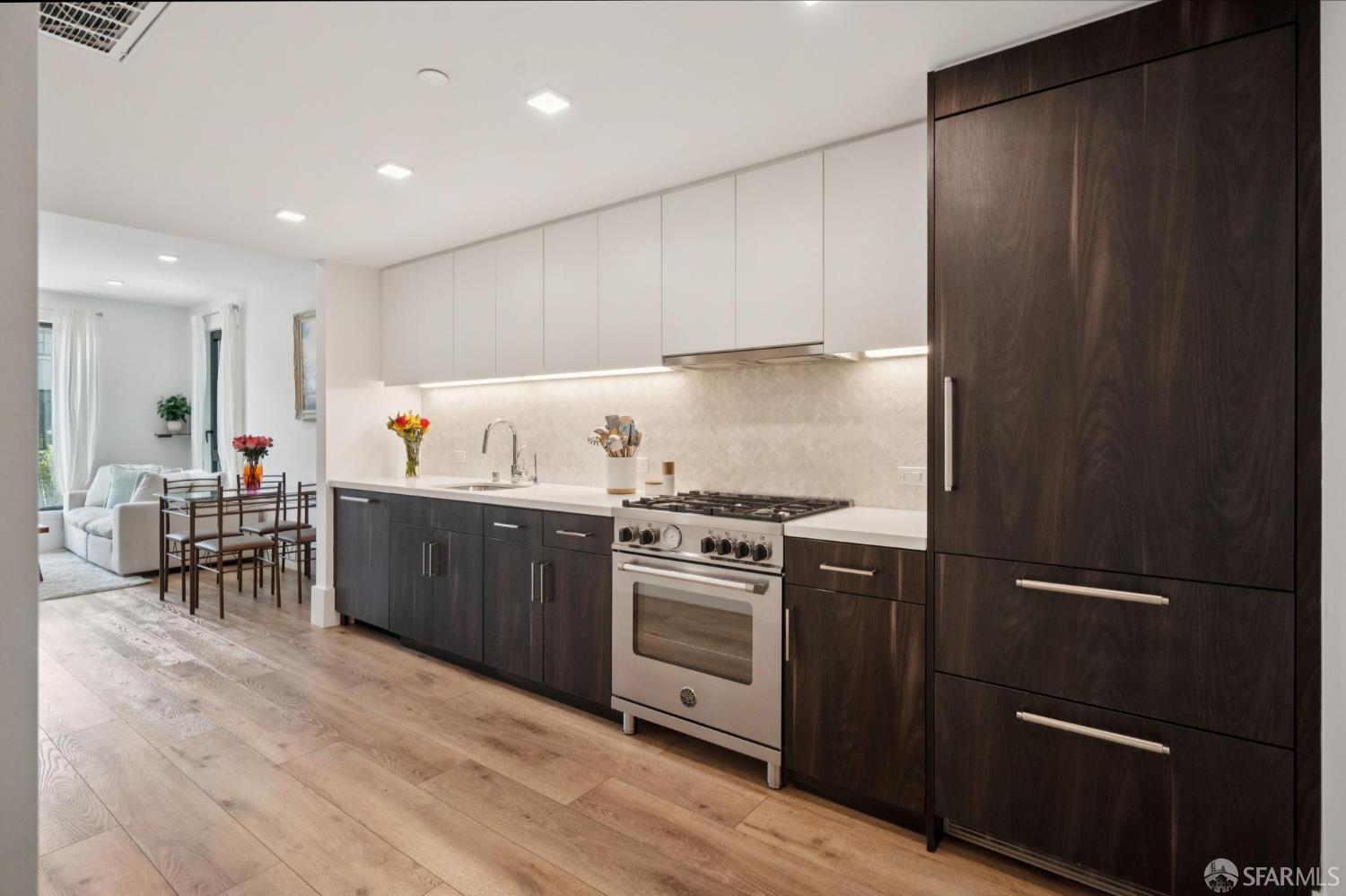 1288 Howard Street, Unit 317 San Francisco, CA 94103 - Photo 9 of 57 a kitchen with granite countertop a refrigerator stove and white cabinets with wooden floor