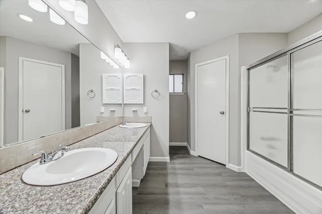 a en suite bathroom with a granite countertop sink shower and a mirror