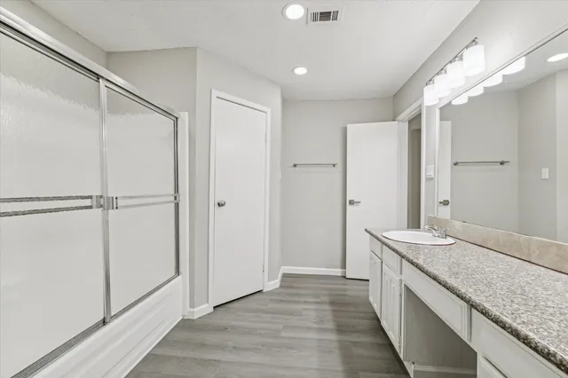 a spacious bathroom with a granite countertop sink a mirror and a shower