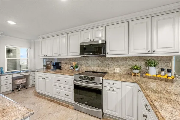 a kitchen with stainless steel appliances granite countertop a refrigerator a sink dishwasher and white cabinets with wooden floor