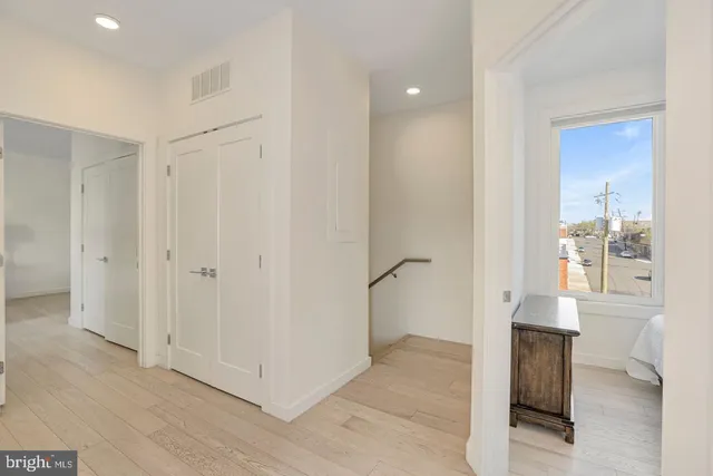 a view of a hallway to an empty room and window
