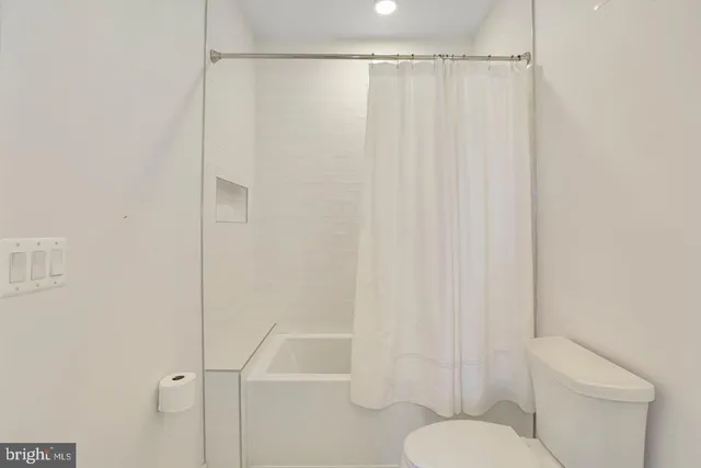a white toilet sitting next to a shower