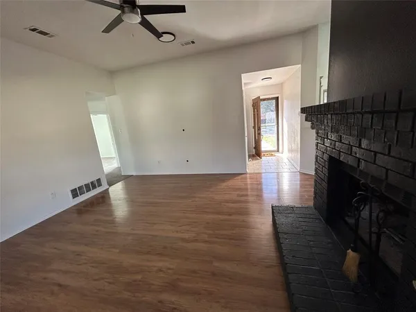 an empty room with wooden floor a fireplace and windows