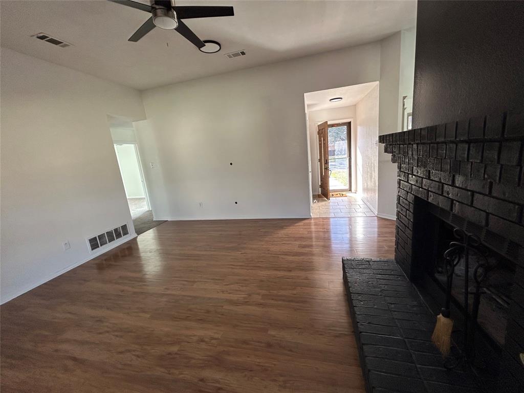 2218 Fuqua Road Rowlett, TX 75088 - Photo 5 of 14 an empty room with wooden floor a fireplace and windows