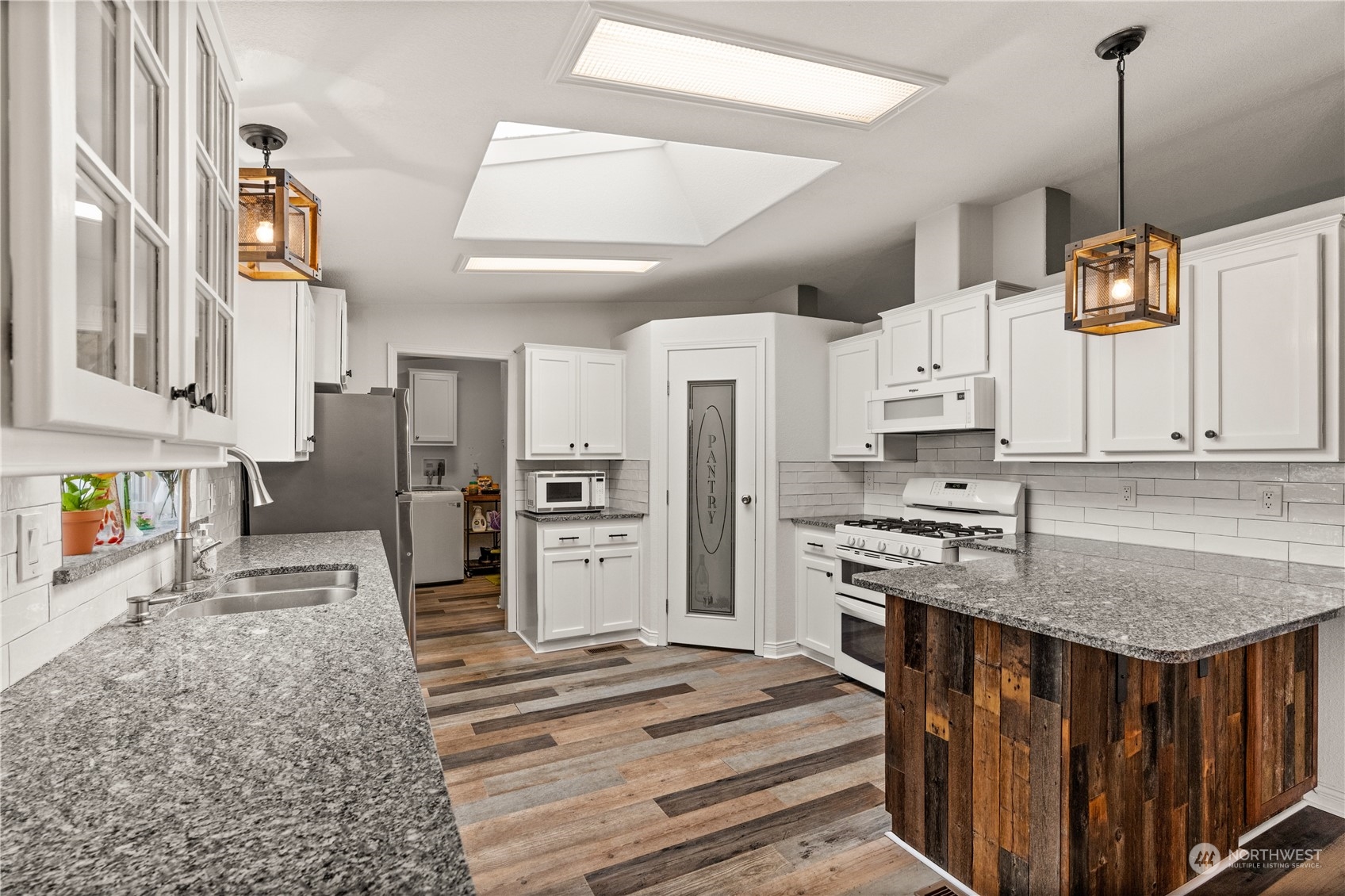 901 West Hendrickson Road Sequim, WA 98382 - Photo 15 of 39 a kitchen with stainless steel appliances granite countertop a stove a refrigerator a sink dishwasher and white cabinets with wooden floor