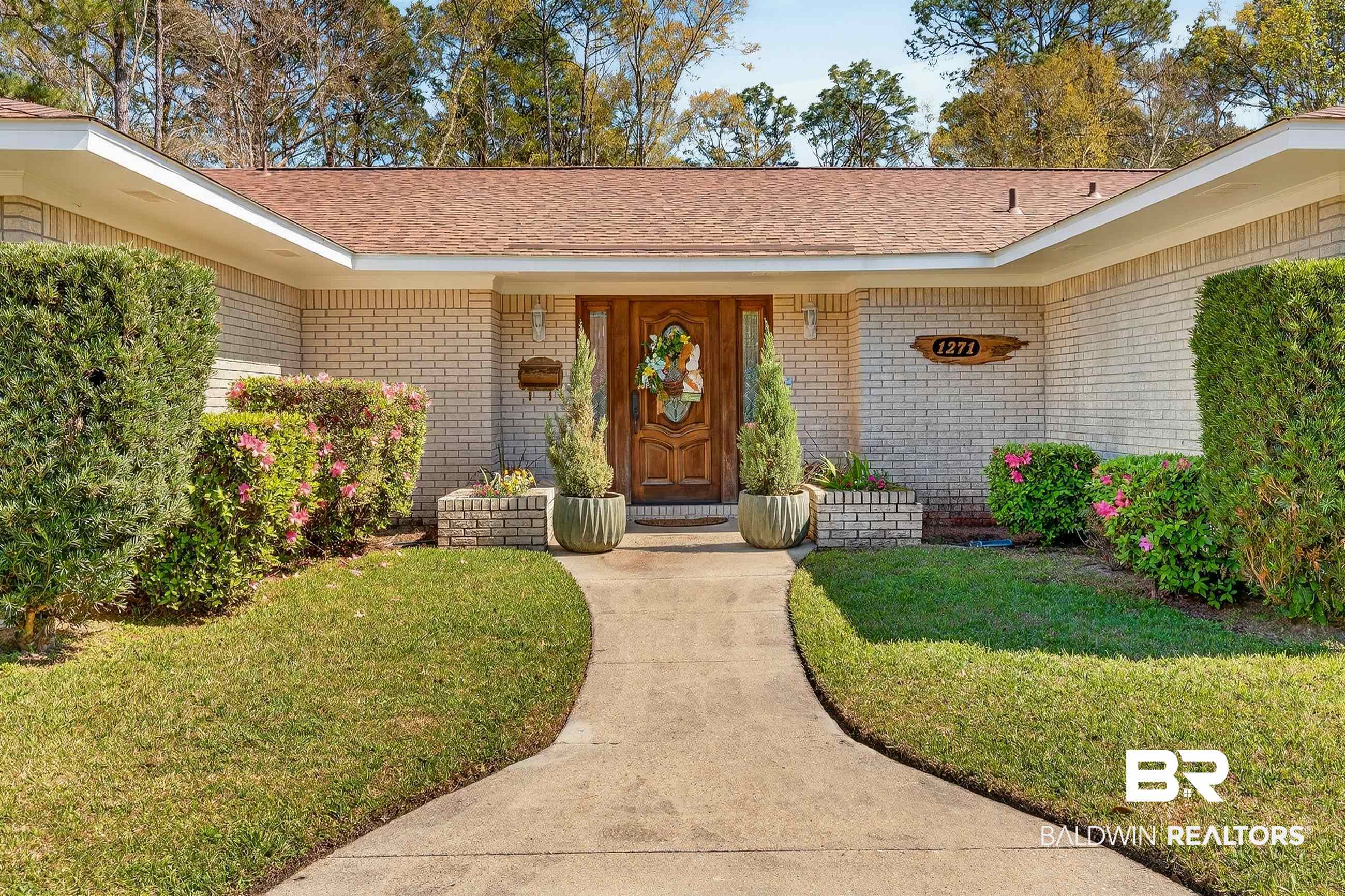1271 Spring Valley Drive South Mobile, AL 36693 - Photo 5 of 56 View of exterior entry featuring brick siding, a shingled roof, and a lawn