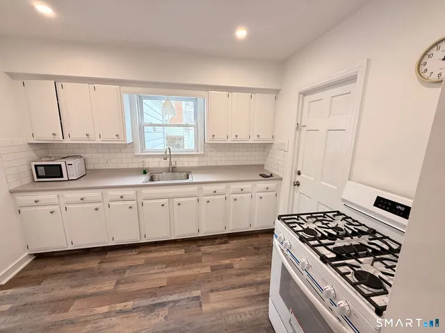 a kitchen with stainless steel appliances a stove a sink and white cabinets