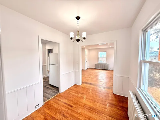 a view of a hallway with wooden floor and a living room