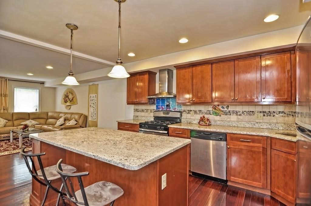 41 Webber Street, Unit 1 Malden, MA 02148 - Photo 4 of 22 a kitchen with a stove a sink dishwasher a kitchen island with chairs and wooden cabinets
