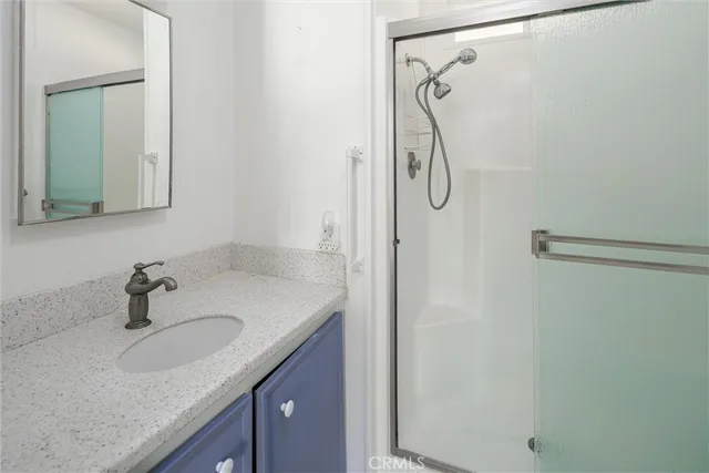 a bathroom with a granite countertop sink a mirror and shower