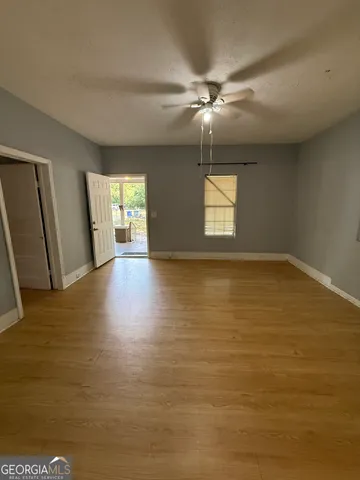 a view of an empty room with window and wooden floor