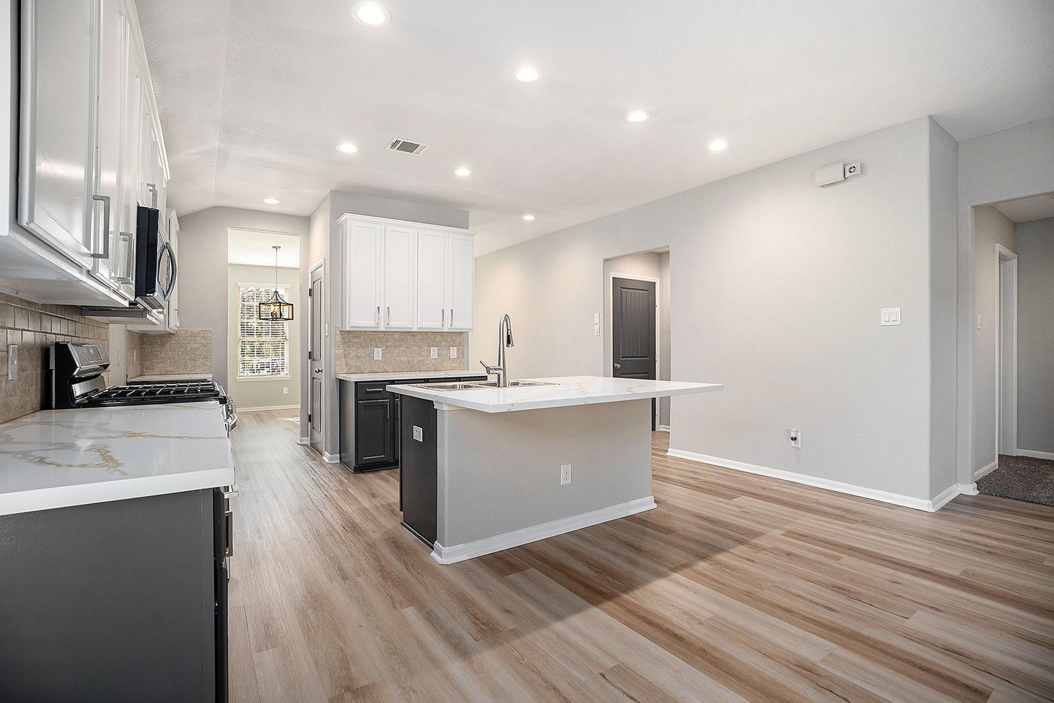 4027 Spurwing Lane Baytown, TX 77521 - Photo 11 of 34 This modern kitchen features sleek white cabinetry, a spacious island with a sink, and stainless steel appliances. The open layout creates a bright and inviting space, perfect for cooking and entertaining.