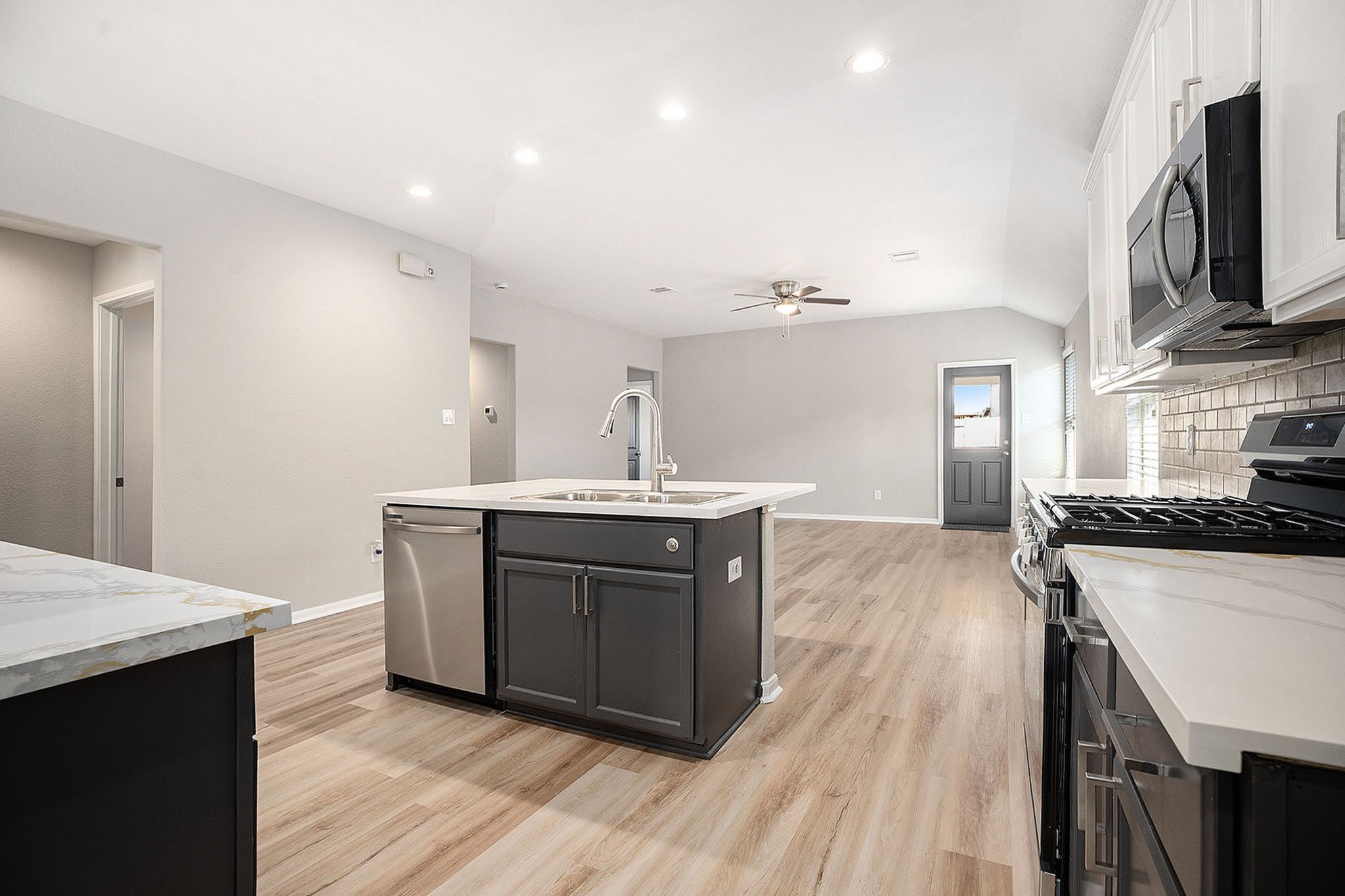4027 Spurwing Lane Baytown, TX 77521 - Photo 13 of 34 This photo showcases a modern, open-concept kitchen with an island and new stainless steel appliances, including a gas stove.