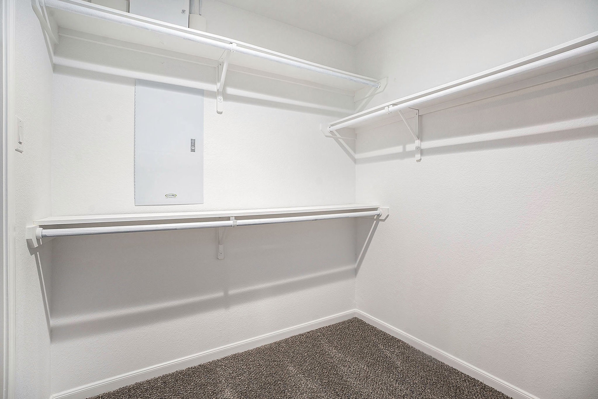 4027 Spurwing Lane Baytown, TX 77521 - Photo 26 of 34 This photo shows a spacious primary walk-in closet with multiple shelves and rods for hanging clothes. The floor is carpeted.