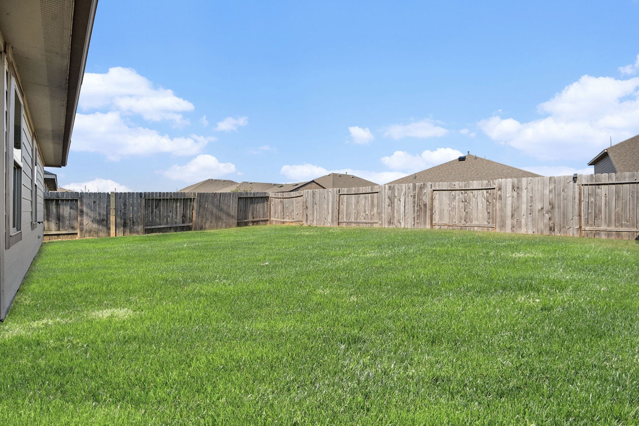 4027 Spurwing Lane Baytown, TX 77521 - Photo 29 of 34 Spacious backyard with lush green grass, bordered by a wooden fence, offering privacy and ample space for outdoor activities.
