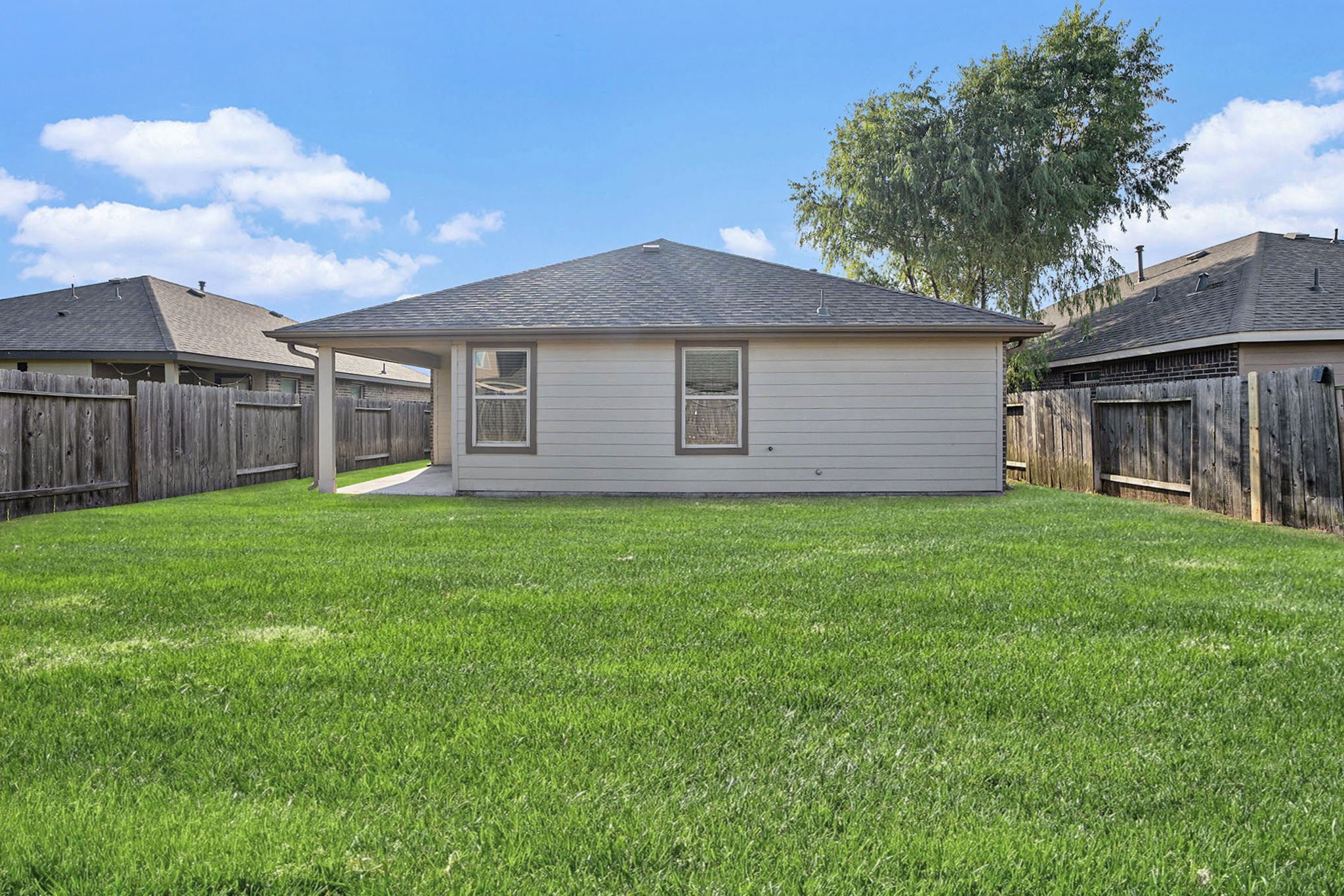 4027 Spurwing Lane Baytown, TX 77521 - Photo 30 of 34 Charming backyard with a well-maintained lawn and a cozy single-story home, perfect for outdoor activities and relaxation.