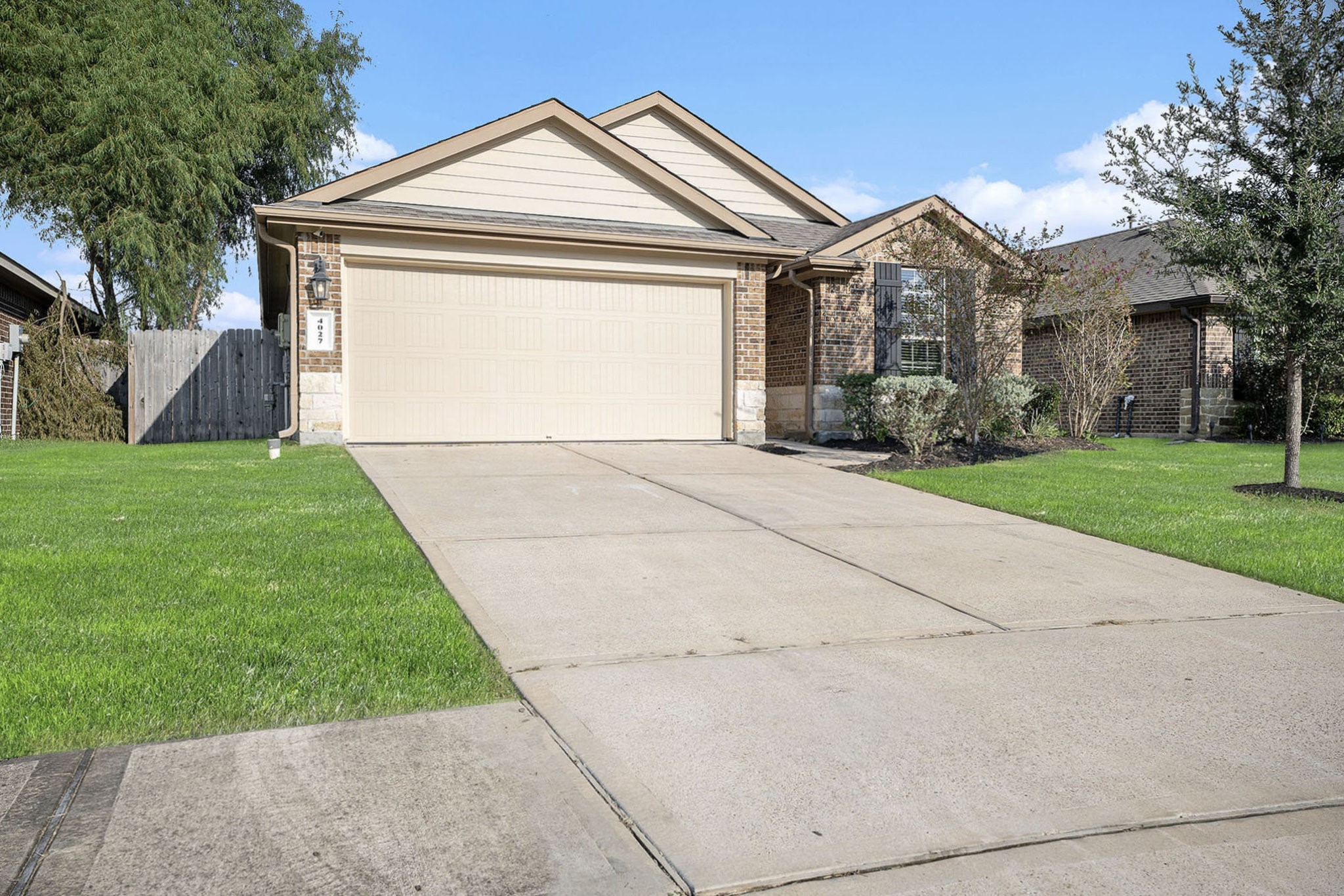 4027 Spurwing Lane Baytown, TX 77521 - Photo 3 of 34 Charming single-story home with a brick exterior and attached two-car garage. It features a well-maintained driveway, manicured lawn, and mature trees for added curb appeal.